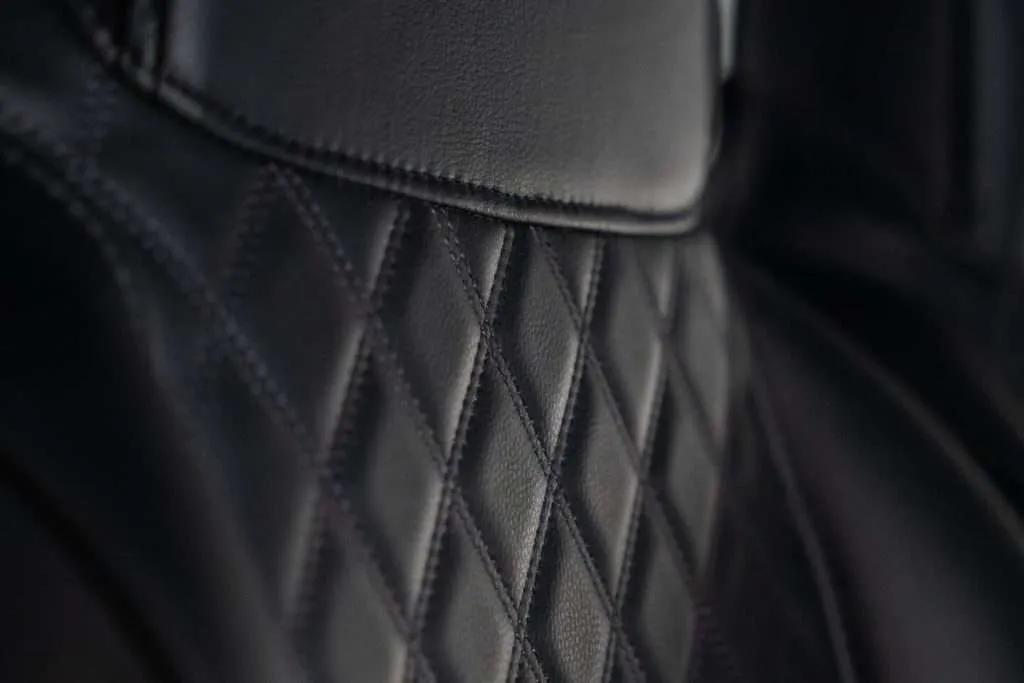 Close-up of black quilted leather upholstery with diamond stitching.