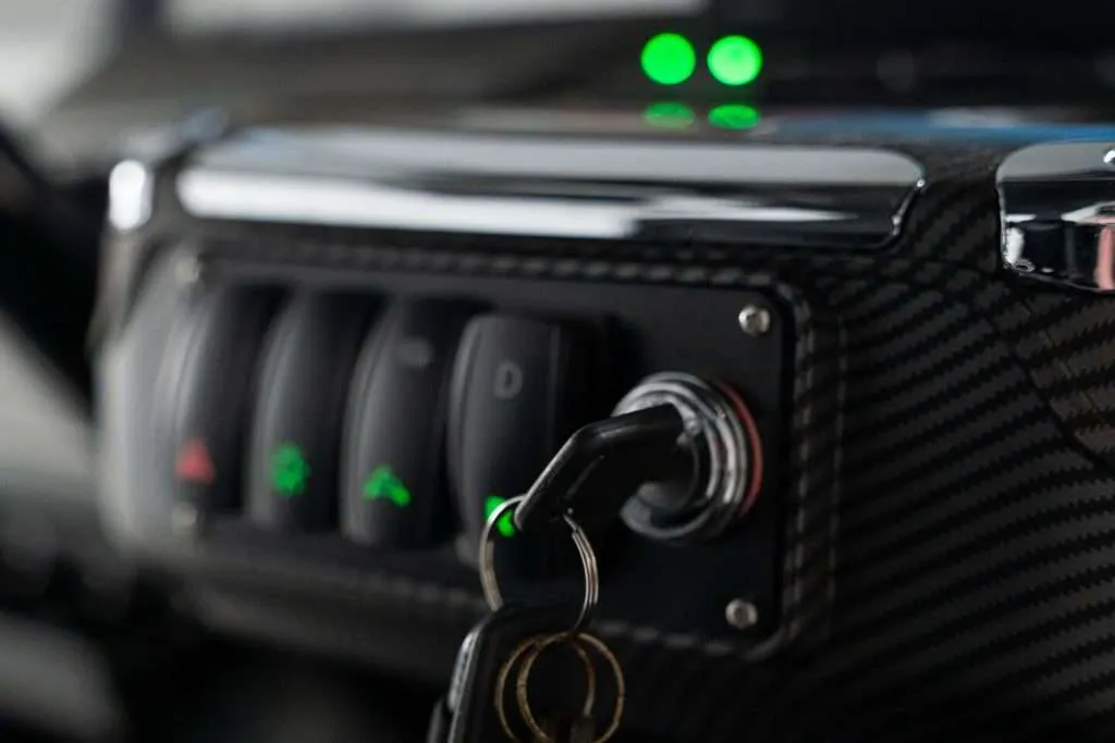 Close-up of a key inserted into a switch on a black panel with green indicators.