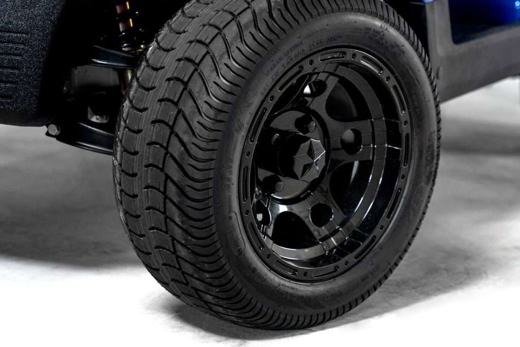 Close-up of a black tire with detailed tread on a shiny black rim.