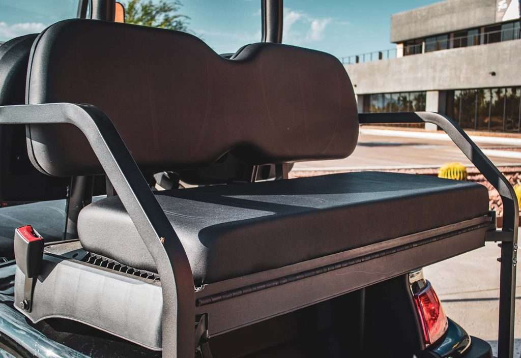 Close-up of a cushioned golf cart seat outdoors.