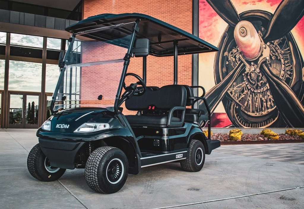 Black golf cart parked near a steampunk-style mural.