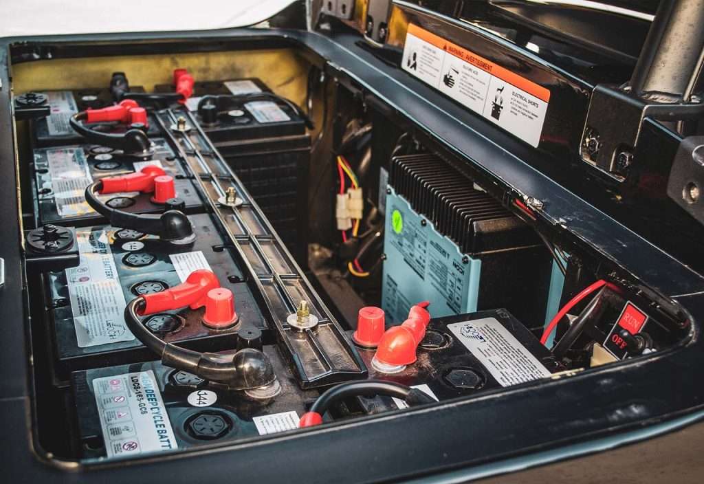 Close-up of a car battery with red and black terminals connected.