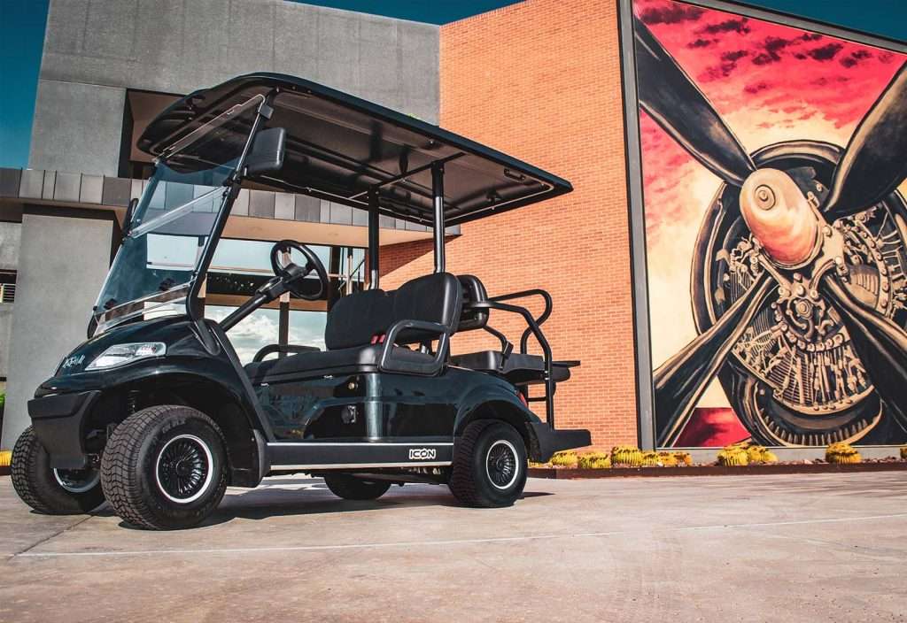 Black golf cart parked near colorful mural wall outdoors.