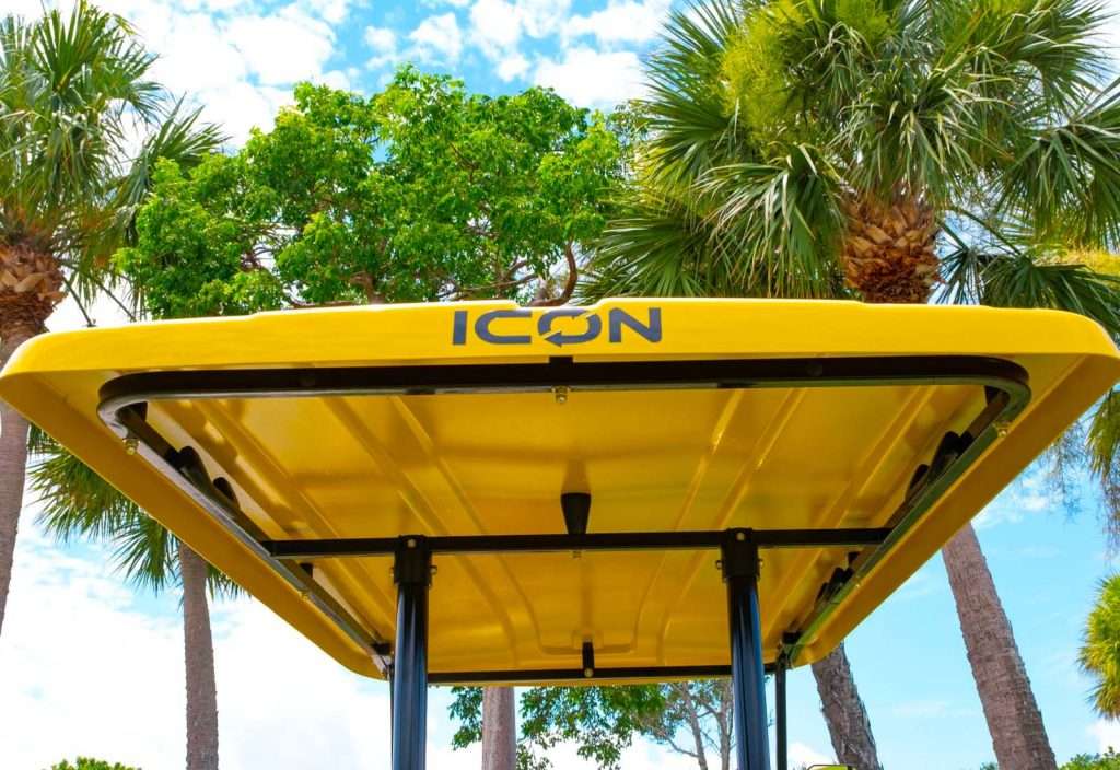 Yellow bus stop shelter with 'ICON' branding under a sunny sky.