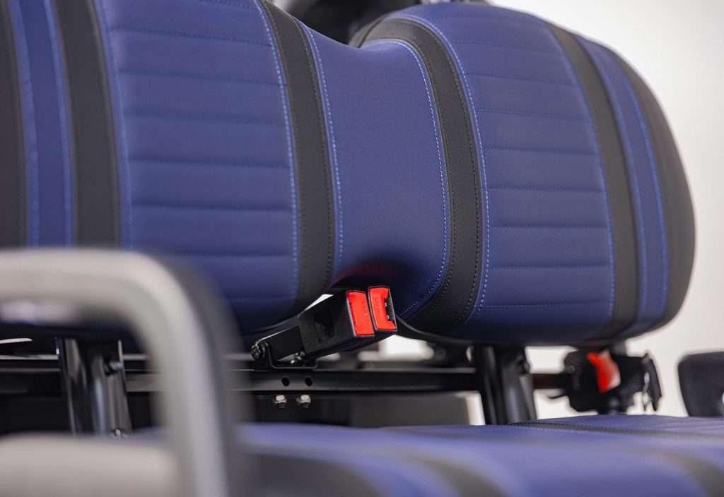 Close-up of blue bus seats with red seatbelt buckles.
