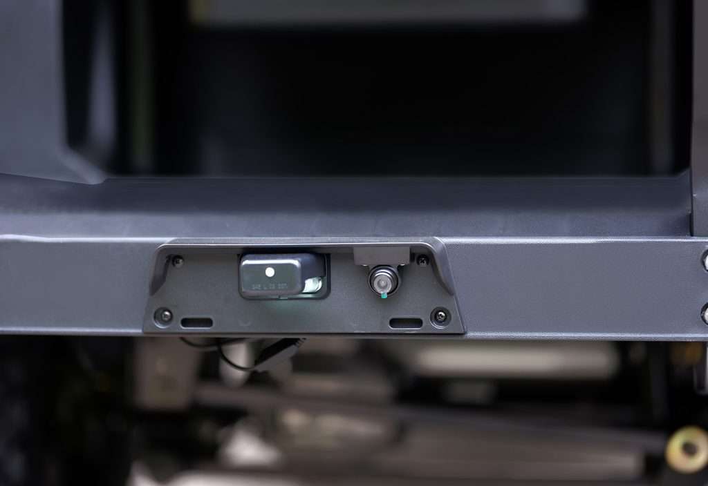 Close-up of a vehicle's trailer hitch receiver under the bumper.