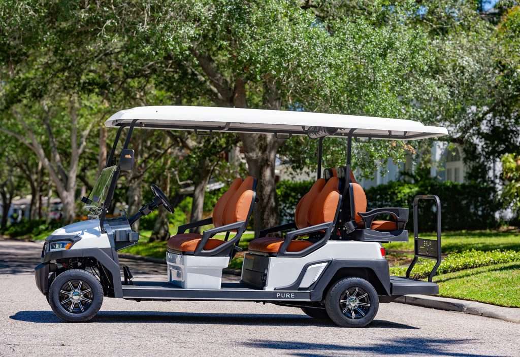 A white golf cart parked on a path surrounded by greenery.