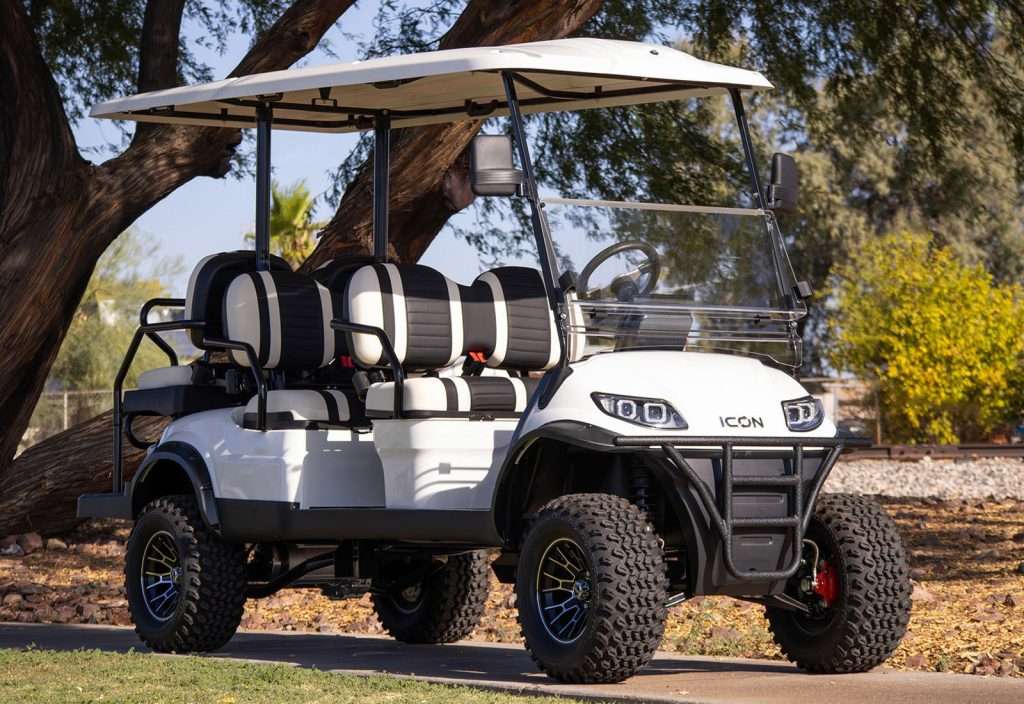 White golf cart parked outdoors with beige seats and a canopy.