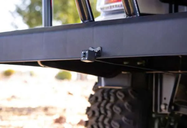 Close-up of a hitch receiver on a vehicle's rear bumper above a large off-road tire.