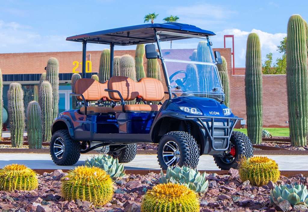 Blue golf cart parked in a desert garden with cacti.