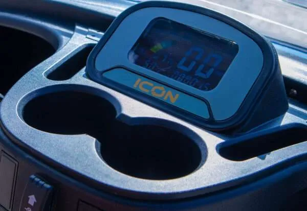 Close-up of a vehicle's dashboard with a digital display and cup holders.