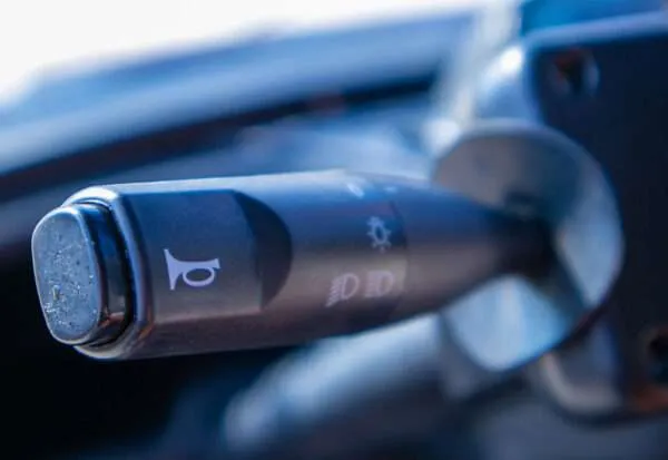 Close-up of a car's turn signal lever with horn symbol.
