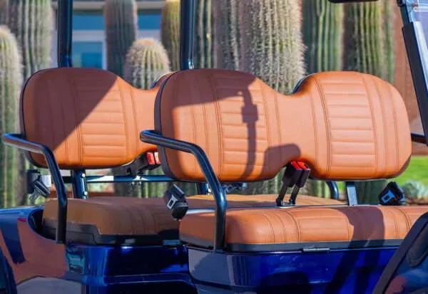 Row of orange seats with black armrests, outdoors near cacti.