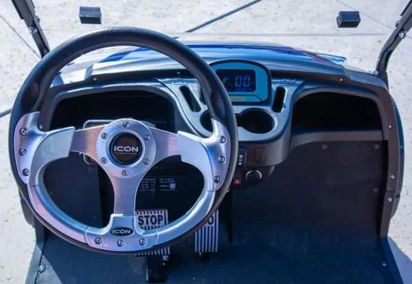 Close-up of a classic car's steering wheel and dashboard with retro design.