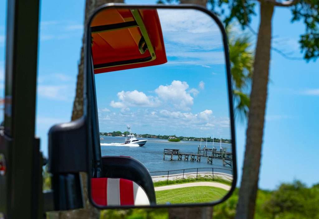 Scenic view of a lake and boats seen through a vehicle's side mirror.