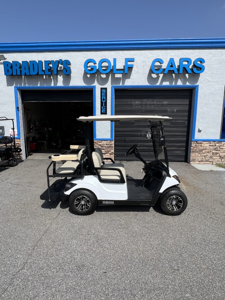 Four-seat white Yamaha golf cart outside shop