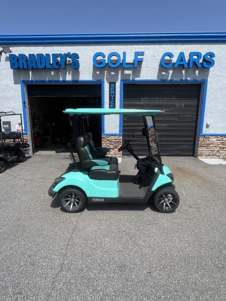 Turquoise Yamaha golf cart parked outside shop