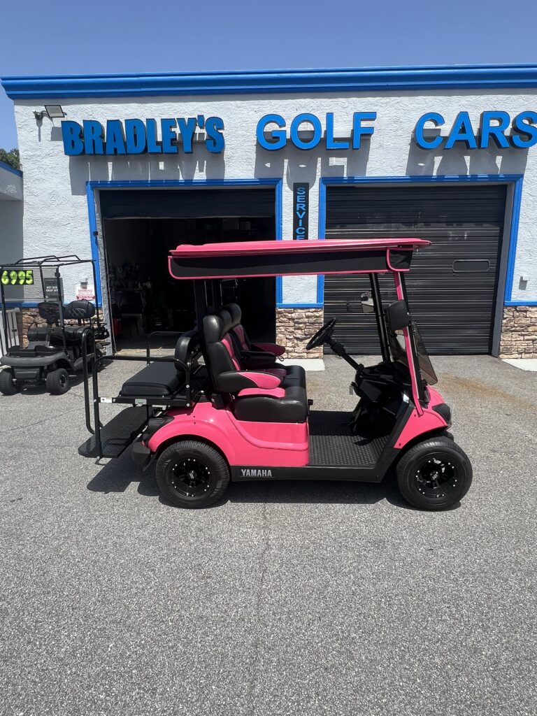 Pink Yamaha golf cart parked outside shop