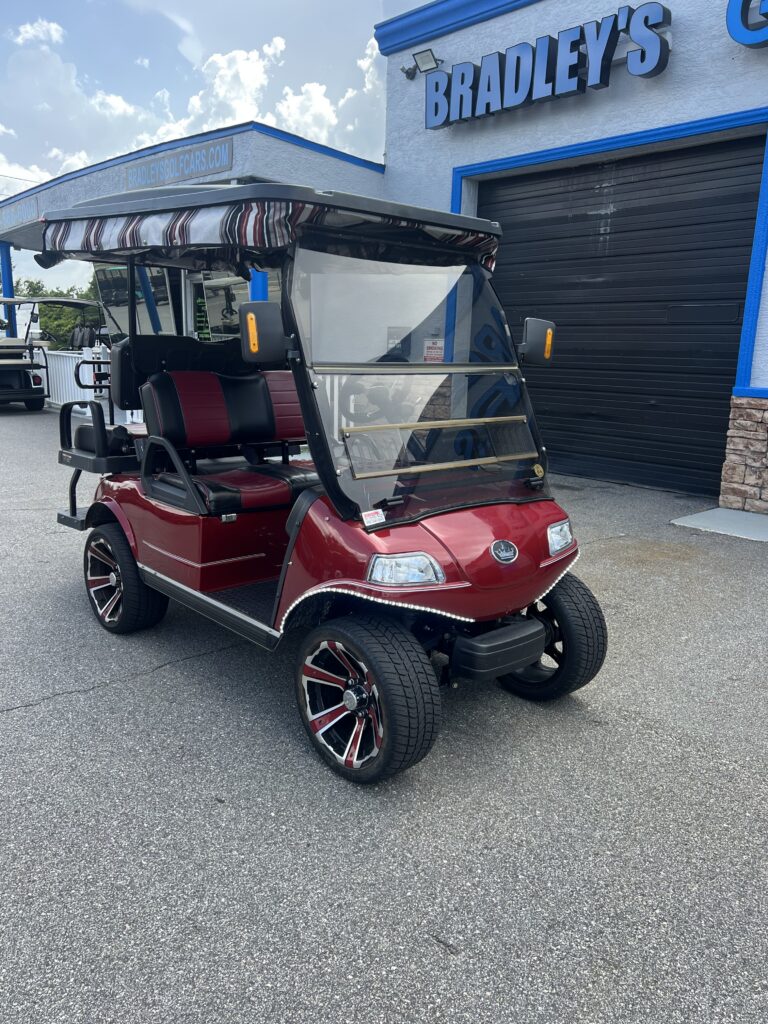 Red golf cart with canopy outside shop